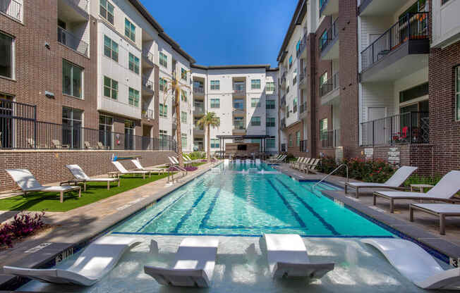 an outdoor pool with lounge chairs and an apartment building