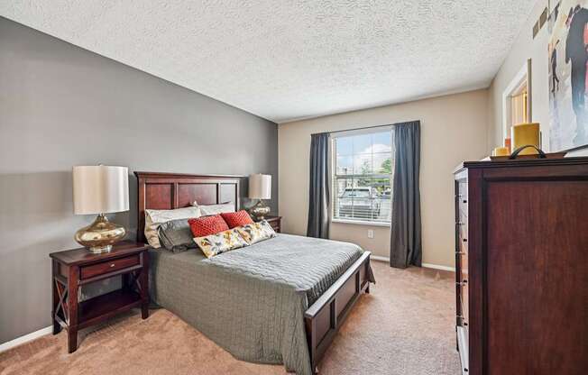 A bedroom with a large bed and a window overlooking a balcony.