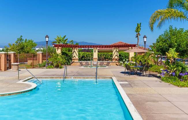 A pool surrounded by a fence and a patio area.