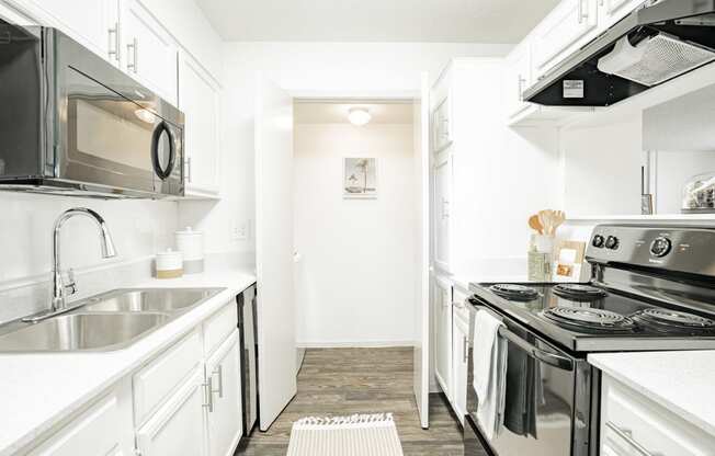 a white kitchen with stainless steel appliances and white cabinets