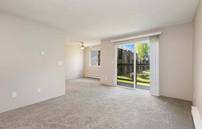 A room with a carpet floor and sliding glass doors leading to a backyard.