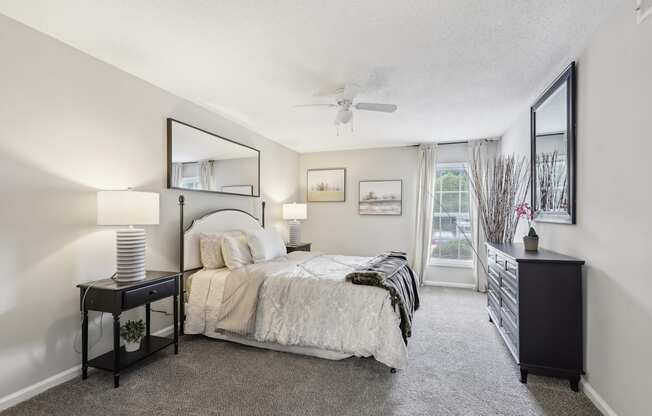 A bedroom with a bed, nightstand, and a window with a view.
