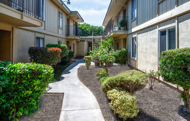 the courtyard of an apartment building with a sidewalk and landscaping