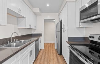 a kitchen with black counter tops and white cabinets