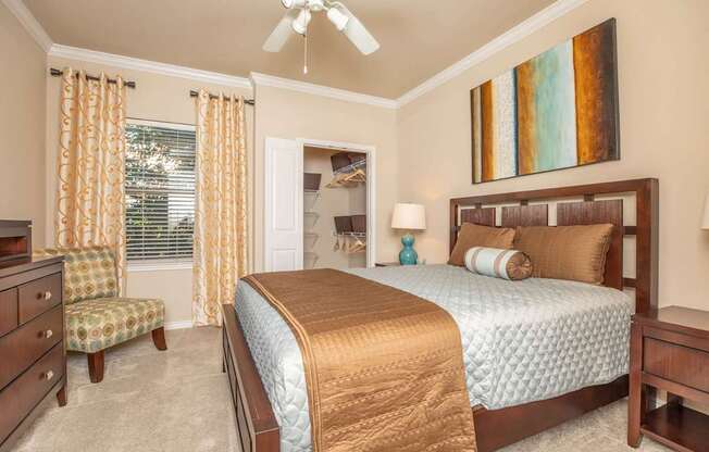 A bedroom with a bed, chair, and a painting on the wall.