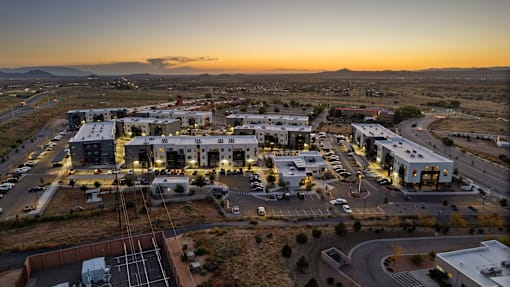 A sunset view of a small town with buildings and a parking lot.