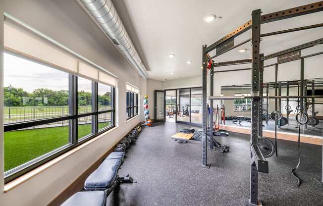 a gym with windows and weights machines and a view of the grass