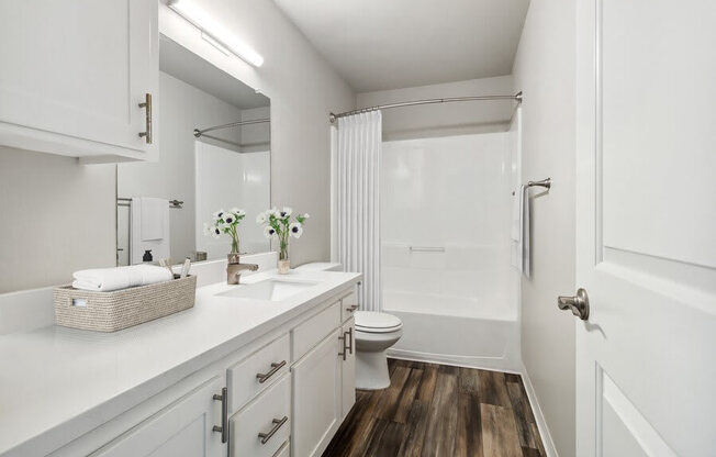 Model Bathroom with Bathtub/Shower, Wood-Style Flooring & White Cabinets at Forest Park Apartments in El Cajon, CA.
