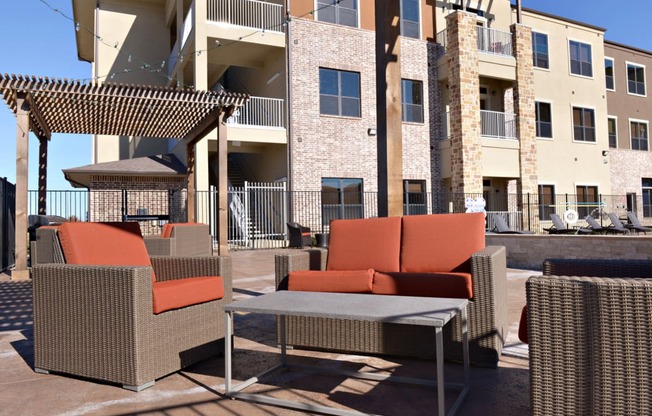 a patio with chairs and a table in front of a building