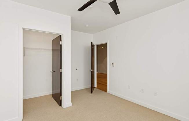 A room with a ceiling fan and two doors.