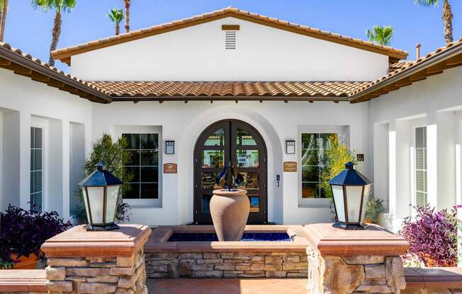 A house with a white facade and a brown roof with a stone wall and a lamp post.