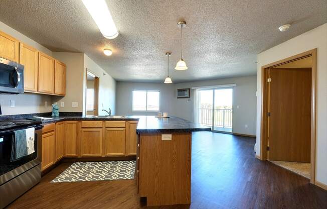 an empty kitchen and living room with wood flooring and a counter top. Fargo, ND East Bridge Apartments