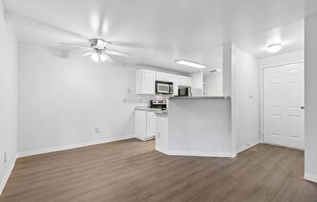 A white kitchen with wood flooring and a ceiling fan.