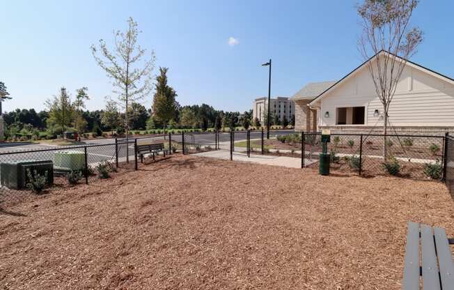 a fenced in dog park with a bench and a building in the background at The Crest at Acworth, Acworth, GA