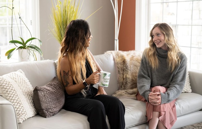 two women sitting on a couch talking