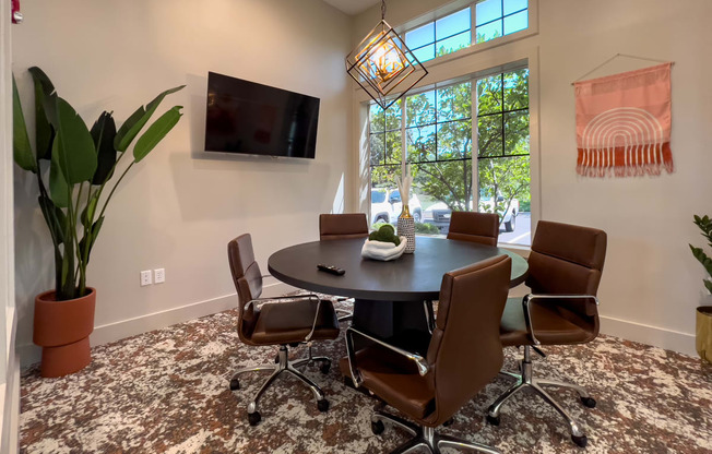 a conference room with a round table and chairs and a television