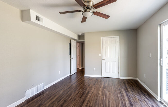 A room with a ceiling fan and wooden floors.
