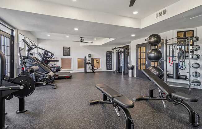 A gym with a variety of equipment including treadmills, weights, and exercise machines.