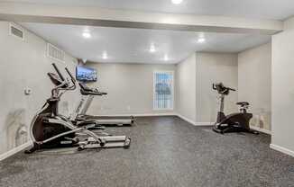 A spacious home gym with a television and exercise equipment.