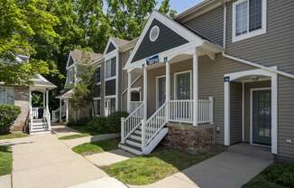 a sidewalk in front of two houses with stairs and a porch