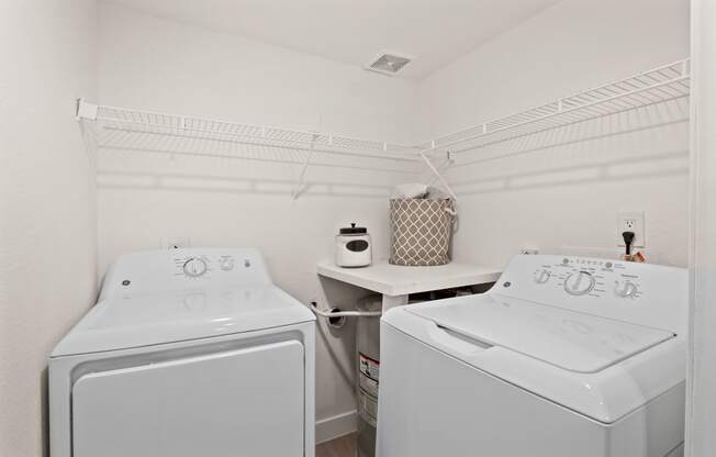 two white washers and dryers in a white laundry room
