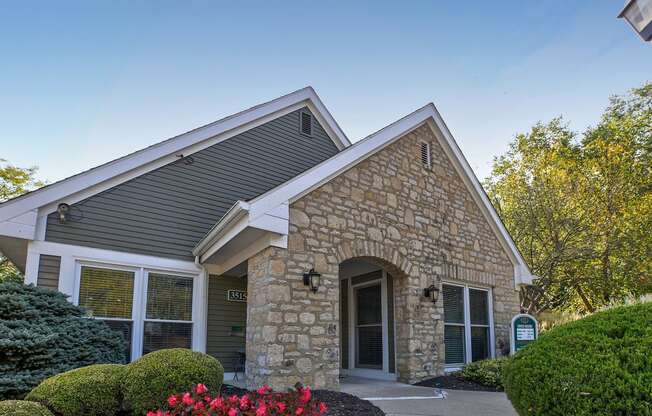 an exterior view of a stone building with a driveway and trees