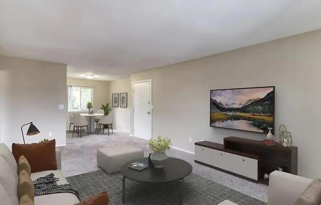 A living room with a grey carpet and a painting on the wall.