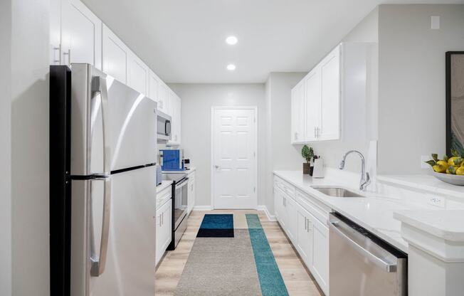 a white kitchen with white cabinets and stainless steel appliances