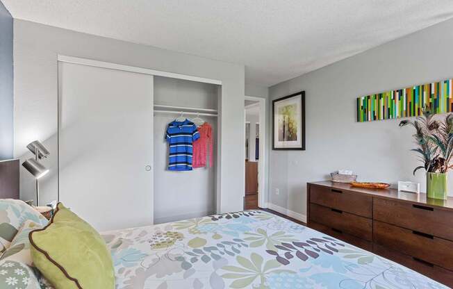 A bedroom with a bed, dresser, and a painting on the wall.