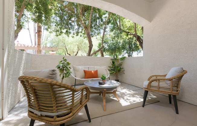 a patio with two rattan chairs and a table