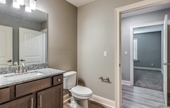 A bathroom with a toilet, sink, and mirror at Mode at Melbourne, LLC Apartments, Florida