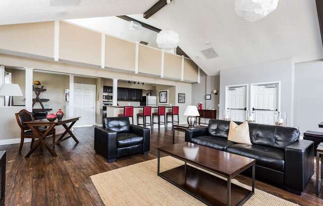 A living room with black leather furniture and a wooden floor.