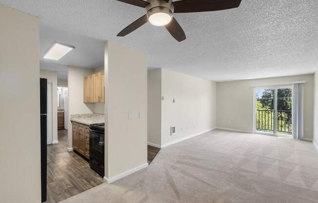 a carpeted living room with a ceiling fan and view of kitchen in the background at Park Edmonds Apartment Homes, Edmonds, 98026