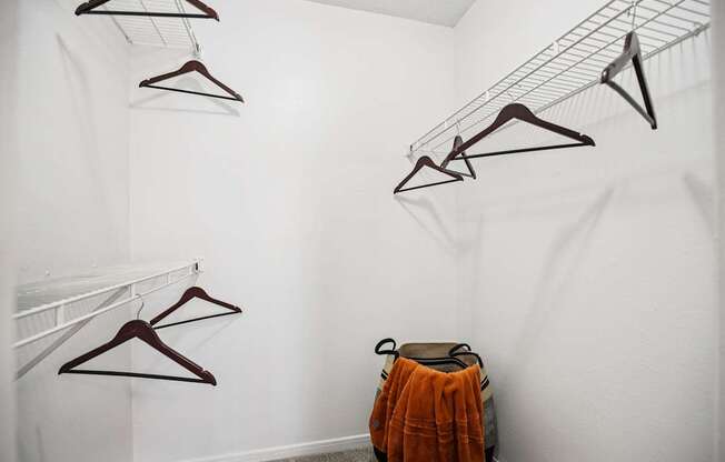 A white wall with clothes hangers and a bag.