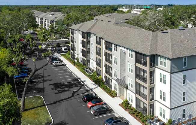 A parking lot in front of a building with cars parked.