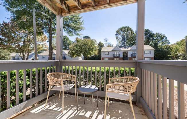 A wooden porch with two chairs and a table.