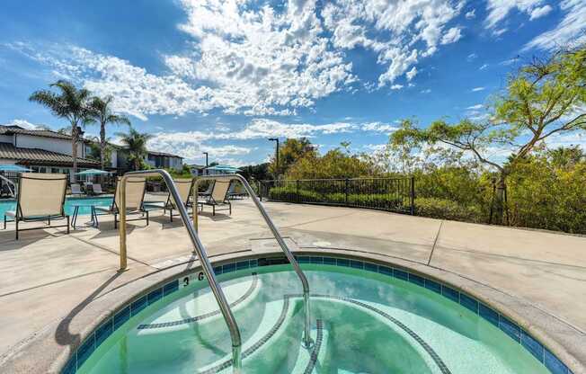 A hot tub sits in the middle of a patio surrounded by chairs.