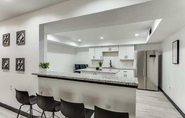 the living room and kitchen of an apartment with a bar and chairs