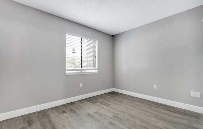 an empty room with wood floors and a window