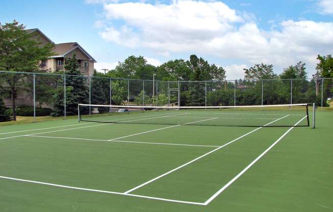 a tennis court with a fence and trees in the background