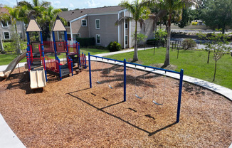 a playground with a swing set in front of a house