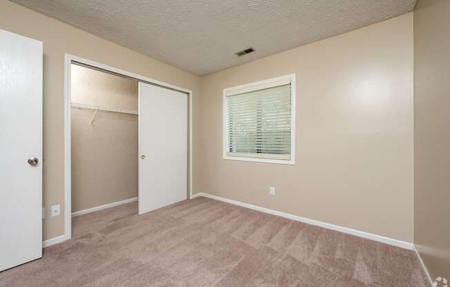 an empty bedroom with a closet and a window