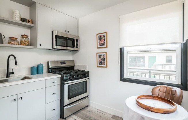 A modern kitchen with white cabinets and a black stove top oven.