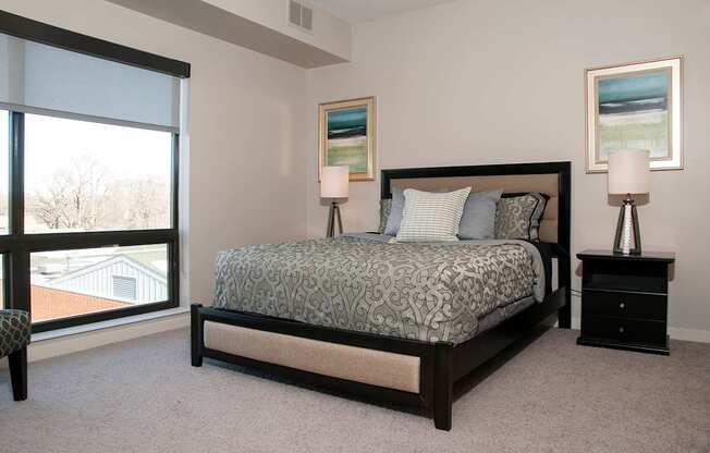 A bedroom with a large bed and two lamps.