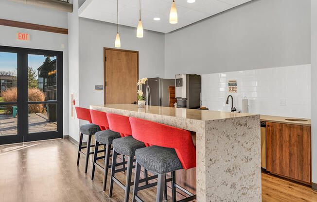 a kitchen with a long island with a row of red bar stools in front of it