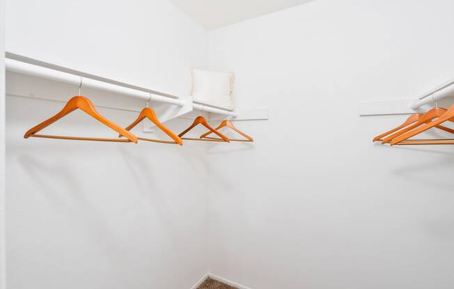 a white closet with orange hangers and white walls
