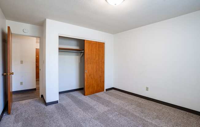 A room with a carpeted floor and a wooden door. Fargo, ND Islander Apartments