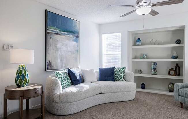 A spacious living room in the model unit of Skyler Ridge Apartments, with a comfortable couch and ceiling fan.