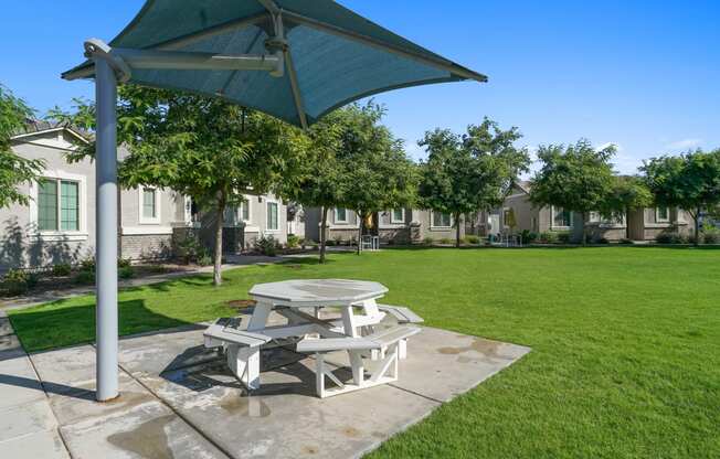 a picnic table with an umbrella on the grass