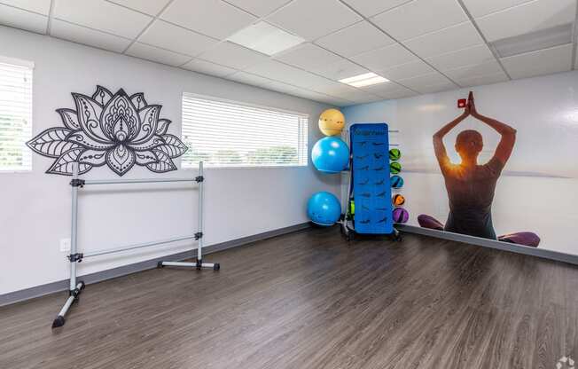 a man doing a yoga pose in a room with a stability ball and a mural